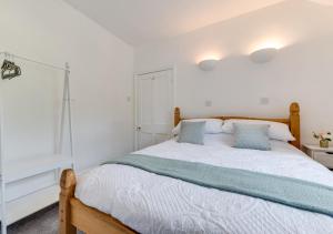 um quarto com uma cama com lençóis brancos e almofadas azuis em 2 Moorcock Cottages em Cotterdale