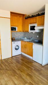 een keuken met witte apparaten en houten kasten bij Font-Romeu : T2 avec grande terrasse et garage in Font Romeu Odeillo Via
