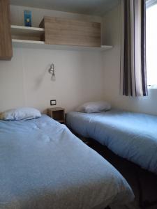 2 camas en una habitación con ventana en MOBIL-HOME 6-8 pers, Domaine de Kerlann 4*, en Pont-Aven