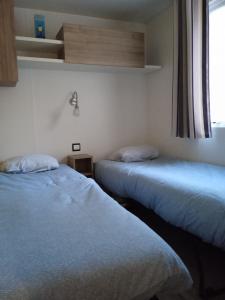 two beds sitting in a room with a window at MOBIL-HOME TOUT CONFORT, 3 CHAMBRES, Domaine de Kerlann in Pont-Aven