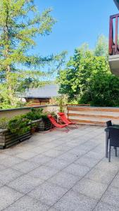 2 chaises rouges assises sur une terrasse à côté d'une clôture dans l'établissement Font-Romeu : T2 avec grande terrasse et garage, à Font-Romeu-Odeillo-Via