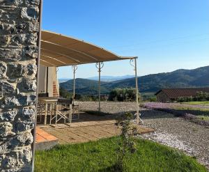ein Steinhaus mit einer Terrasse mit einem Tisch und einem Sonnenschirm in der Unterkunft Agriturismo il Ghiaccio in Suvereto