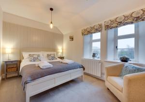 a bedroom with a bed and a chair and windows at 2 Railway Cottages in Selside