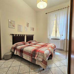 1 dormitorio con 1 cama con manta a cuadros y ventana en CASA OLTREPO silenziosa comoda centrale e parcheggio interno, en Casteggio