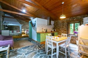 a kitchen and dining room with a table and chairs at Casas del Molino - Muiños do Mainzoso Turismo Rural in Paderne