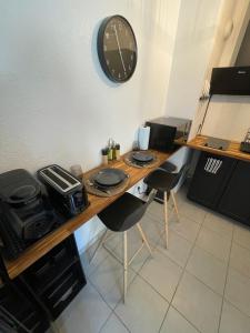 une table avec deux chaises et une horloge sur le mur dans l'établissement Appartement en résidence-Avignon, à Avignon