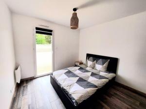 um quarto com uma cama em preto e branco e uma janela em La Maison de Kahyna classé 3 étoiles em Roiffé