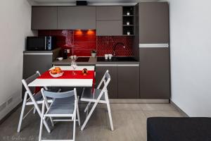 a kitchen with a red and white table and chairs at Sikelia Apartments in Pozzallo