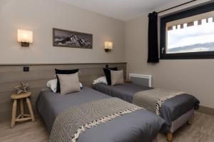 two beds in a room with a window at Chalets Residence Snoweden in Montchavin