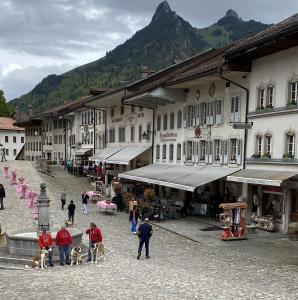 a group of people and dogs in a town with buildings at Gruyère Rooms in Gruyères