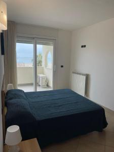 a bedroom with a blue bed and a balcony at BILOCALE FRONTE MARE in Rimini