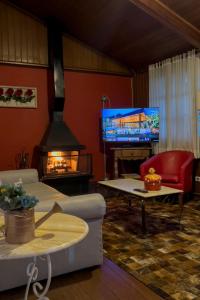a living room with a fireplace and a television at Pousada Do Conde in Campos do Jordão