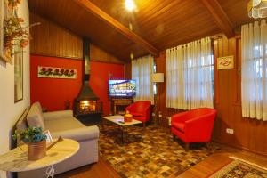 uma sala de estar com mobiliário vermelho e uma televisão em Pousada Do Conde em Campos do Jordão