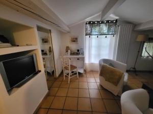 un salon avec une télévision et une table avec des chaises dans l'établissement La haute verrerie, au Cannet-des-Maures