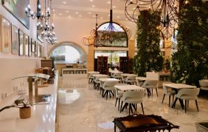 a restaurant with white tables and chairs and a chandelier at Lagos Atlantic Hotel in Lagos