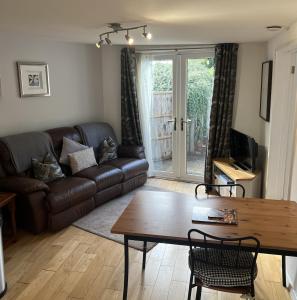 a living room with a leather couch and a table at The Garden Apartment in Ironbridge