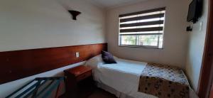 a small bedroom with a bed and a window at Nativo Hotel y Cafeteria in Talca
