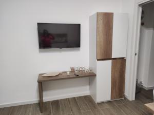 Una habitación con una mesa y un televisor en una pared. en Kitros, en Palagiano