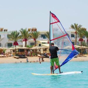 a man on a surfboard with a sail on the beach at chalets Mirage beach in Hurghada