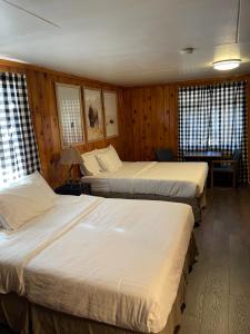 three beds in a room with wooden walls and windows at The Spruce Lodge in South Fork