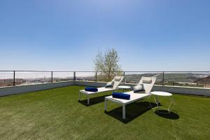 uma varanda com duas cadeiras e uma mesa na relva em Ground floor 4 Bedroom Apartment @ Estepona Hills! em Estepona
