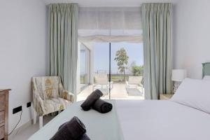 um quarto com uma cama, uma cadeira e uma janela em Ground floor 4 Bedroom Apartment @ Estepona Hills! em Estepona