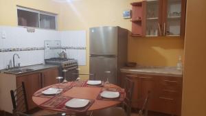 uma cozinha com uma mesa e um frigorífico de aço inoxidável em Casas Particulares, Tipo Cabañas. em San Pedro de Atacama