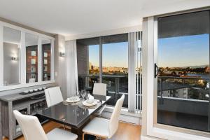 a dining room with a table and chairs and windows at Harbour Walk Executive Condo in Victoria