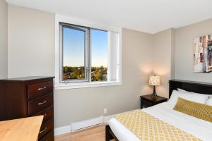 a bedroom with a bed with a desk and two windows at Harbour Walk Executive Condo in Victoria