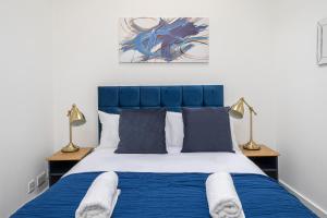 een slaapkamer met een blauw en wit bed met 2 lampen bij Spacious and Comfy 4 Bedroom House near Oxford Street and marble Arch in Londen