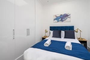 een slaapkamer met een blauw en wit bed met handdoeken erop bij Spacious and Comfy 4 Bedroom House near Oxford Street and marble Arch in Londen