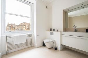 een badkamer met een toilet, een wastafel en een raam bij Spacious and Comfy 4 Bedroom House near Oxford Street and marble Arch in Londen