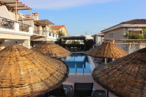 a group of straw umbrellas sitting next to a pool at Fizzio Alaçatı Hotel in Alaçatı