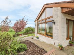 a stone cottage with large windows and a garden at Laird House in Lockerbie