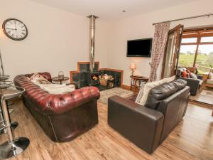 een woonkamer met lederen meubels en een open haard bij Laird House in Lockerbie