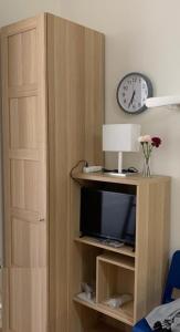 a wooden cabinet with a tv and a clock at Side Street Apartments in Prague