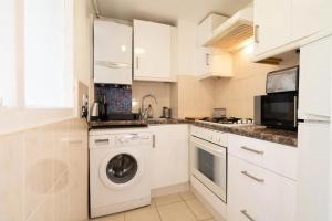 a white kitchen with a washing machine in it at Lovely Entire Flat in Kings Cross in London