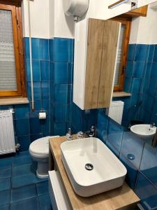 a blue tiled bathroom with a sink and a toilet at Coral Apartment in Nettuno