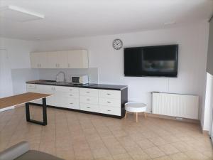 uma cozinha com armários brancos e uma televisão na parede em Mesgye Villa em Balatonalmádi