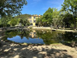 un étang en face d'une grande maison dans l'établissement BASTIDE DU DEFENDS, à Pertuis