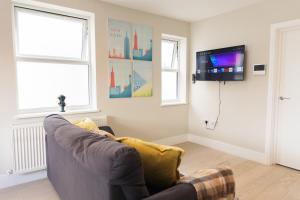 a living room with a couch and a flat screen tv at Star London Bell Lane 3-Bed Haven in Hendon