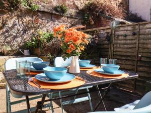 a table with plates and bowls and a vase of flowers at Navigators Rest in Whitby