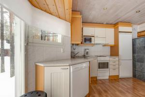 a kitchen with white appliances and a wooden ceiling at Tapola in Kalajoki