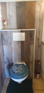 een badkamer met een blauw toilet en een houten muur bij Le Fier Paon 