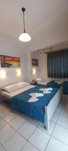 1 dormitorio con 2 camas con sábanas azules y lámpara en Fotini's Beach, en Olympiakí Aktí