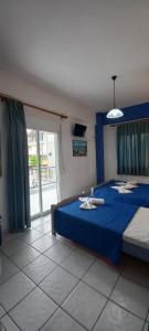 1 dormitorio con cama azul y ventana grande en Fotini's Beach, en Olympiakí Aktí