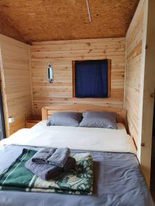 Cama en una cabaña de madera con ventana en Lake House Perucac en Rastište