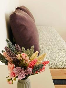 een vaas gevuld met bloemen op een tafel naast een bed bij N'amuri Guest House in Siracusa