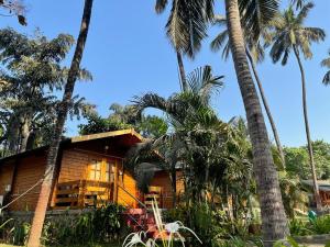 a wooden house with palm trees in front of it at Casa de Kihim in Alibaug