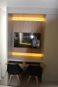 a tv on a wall with two people on it at Loft aconchegante à Beira-Mar in João Pessoa +19 photos